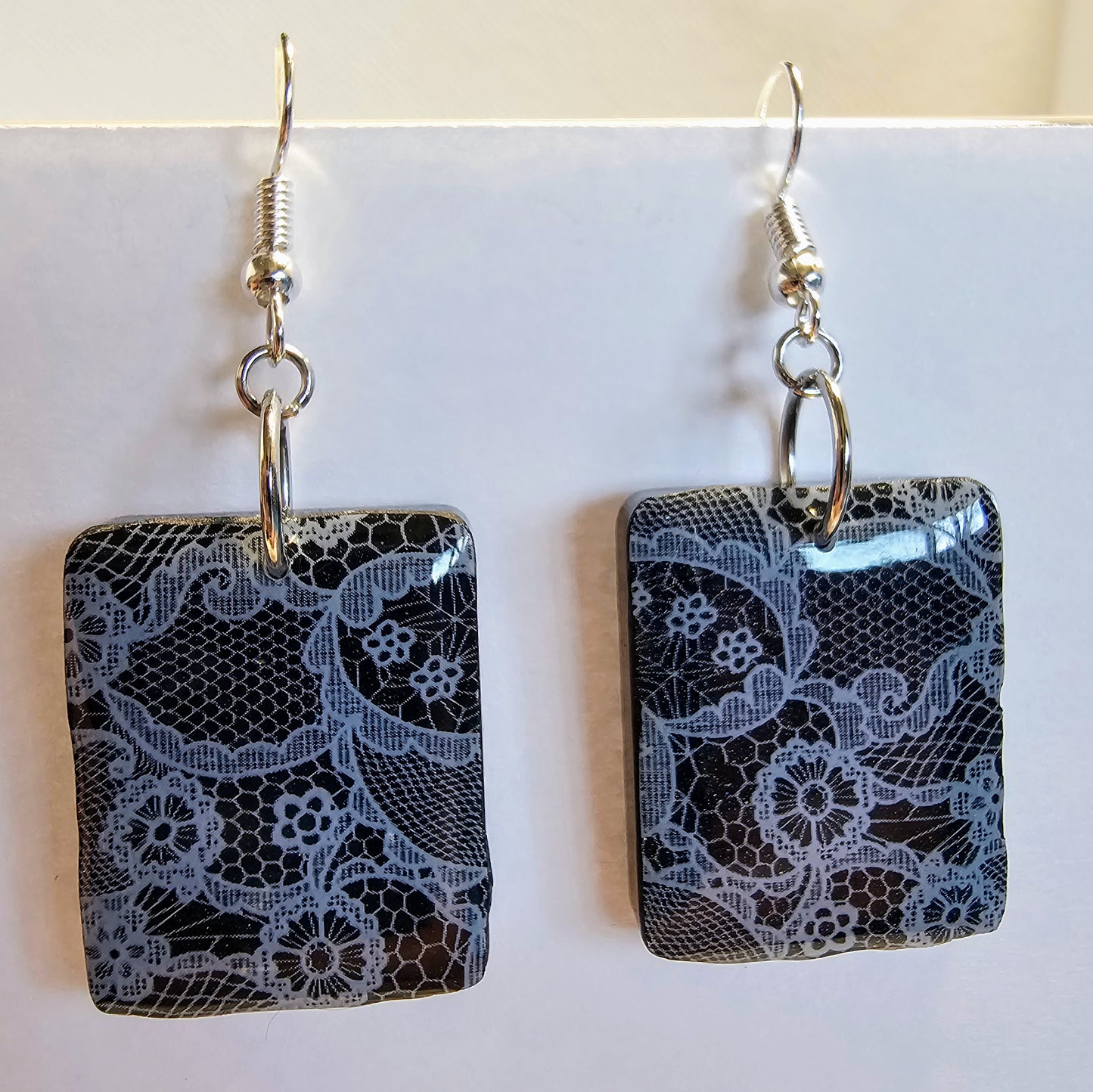 Delicate white lace earrings on a black background