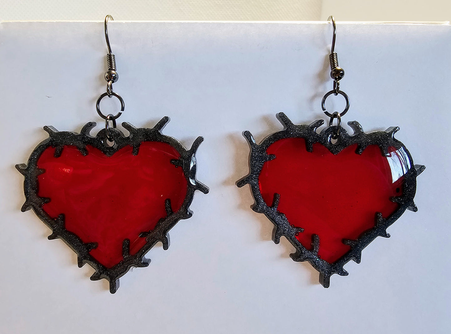 Heart shaped barbed wire earrings with a ruby red center