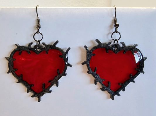 Heart shaped barbed wire earrings with a ruby red center